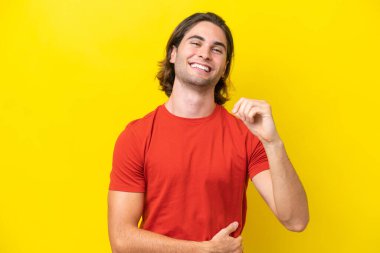 Caucasian handsome man isolated on yellow background laughing
