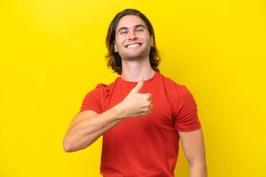 Caucasian handsome man isolated on yellow background giving a thumbs up gesture