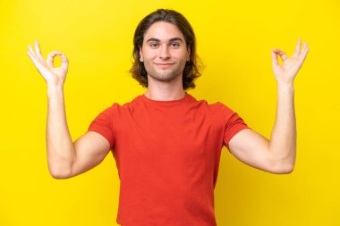 Caucasian handsome man isolated on yellow background in zen pose