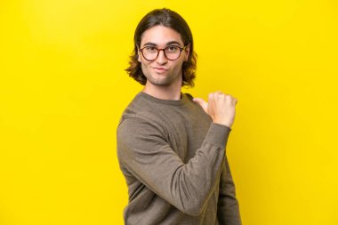 Beyaz tenli yakışıklı adam sarı arka planda soyutlanmış gururlu ve kendini beğenmiş.