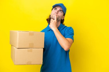 Sarı arka planda izole edilmiş yakışıklı bir adam yukarı bakarken şüpheleri var.