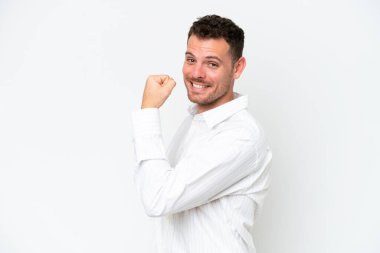Beyaz arka planda izole edilmiş beyaz, yakışıklı genç bir adam güçlü bir jest yapıyor.