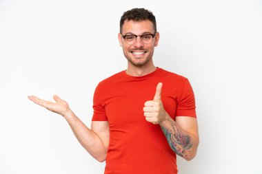 Beyaz arka planda izole edilmiş beyaz tenli yakışıklı bir adam bir reklam vermek ve onaylamak için avucunda hayali bir fotokopi makinesi tutuyor.