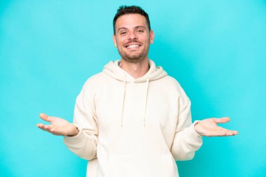 Kafkasyalı yakışıklı genç adam mavi arka planda izole edilmiş şüpheleri var.