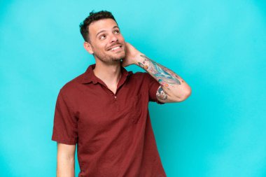 Kafkasyalı yakışıklı genç bir adam mavi arka planda izole edilmiş bir fikir düşünüyor.