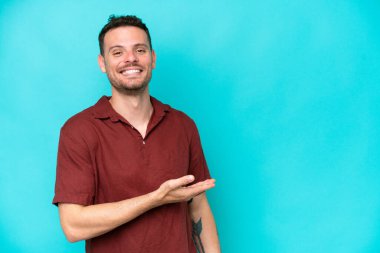 Beyaz tenli yakışıklı adam mavi arka planda izole edilmiş bir şekilde bir fikir sunuyor.