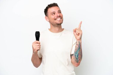 Beyaz arka planda izole edilmiş bir mikrofonu eline alan beyaz tenli genç şarkıcı harika bir fikre işaret ediyor.