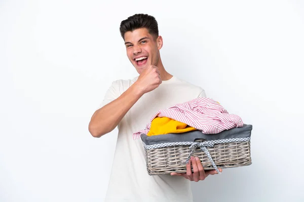 stock image Young caucasian man holding laundry basket isolated on white background celebrating a victory