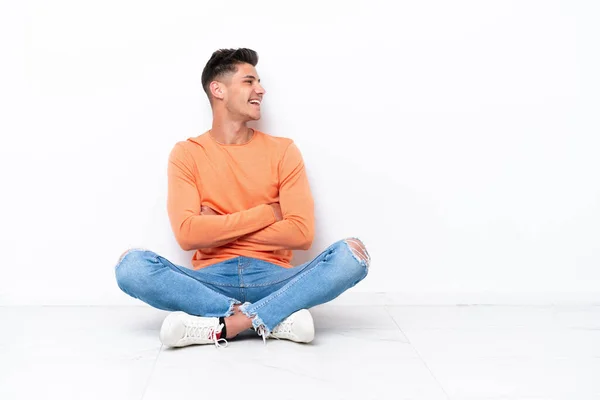 Yerde Oturan Genç Adam Beyaz Arka Planda Tek Başına Mutlu — Stok fotoğraf