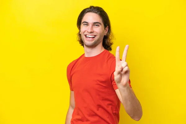 Kaukasische Knappe Man Geïsoleerd Gele Achtergrond Glimlachend Met Overwinningsteken — Stockfoto