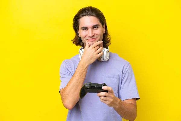 Молодой Красивый Белый Мужчина Играющий Игровым Контроллером Жёлтом Фоне Думает — стоковое фото