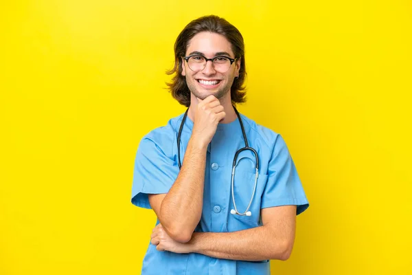若いです外科医Caucasian男隔離上の黄色の背景に眼鏡と笑顔 — ストック写真