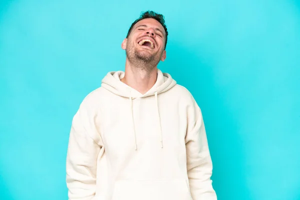 stock image Young caucasian handsome man isolated on blue background laughing