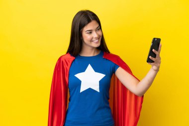 Süper kahraman Brezilyalı kadın sarı arka planda izole edilmiş selfie çekiyor.