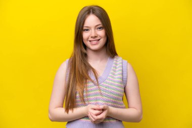 Sarı arka planda izole edilmiş genç beyaz kadın gülüyor.