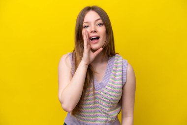 Sarı arka planda izole edilmiş genç beyaz kadın ağzı açık bağırıyor.