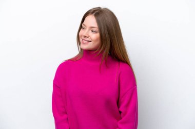 Beyaz arka planda izole edilmiş genç beyaz kadın yan bakıyor ve gülümsüyor.