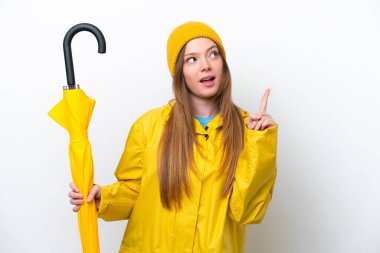 Yağmura dayanıklı ceketi ve şemsiyesi olan beyaz arka planda izole genç, beyaz bir kadın.