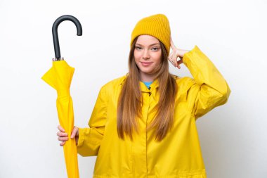 Yağmura dayanıklı paltosu ve şemsiyesi olan beyaz arka planda yalnız beyaz bir kadın. Şüpheleri ve düşünceleri var.