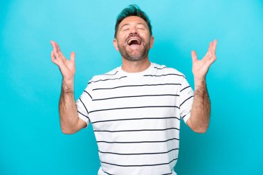 Orta yaşlı beyaz bir adam mavi arka planda izole edilmiş, çok gülümsüyor.