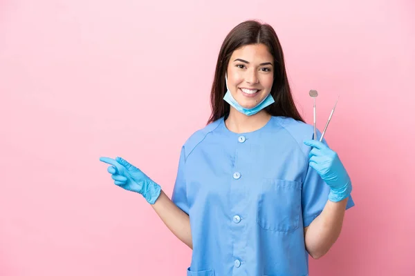 Dentista Mulher Segurando Ferramentas Isoladas Fundo Rosa Apontando Dedo Para — Fotografia de Stock