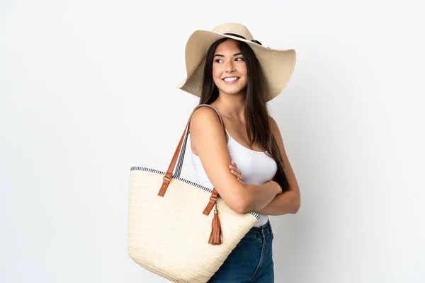 stock image Young Brazilian woman with Pamela holding a beach bag isolated on white background with arms crossed and happy