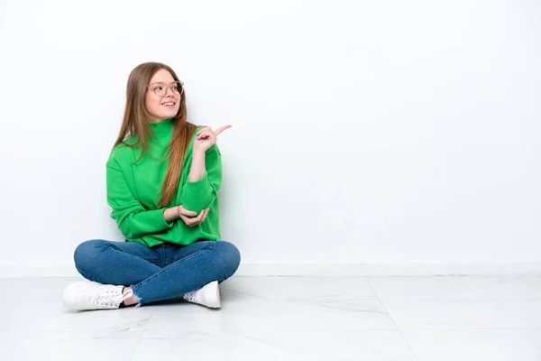 Молода Біла Жінка Сидить Підлозі Ізольована Білому Тлі Вказуючи Пальцем — стокове фото