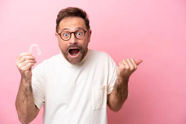 Middle Age Man Holding Invisible Braces Isolated Pink Background Surprised — Stock Photo, Image