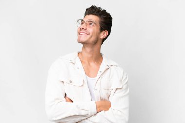 Young handsome caucasian man over isolated white background looking up while smiling