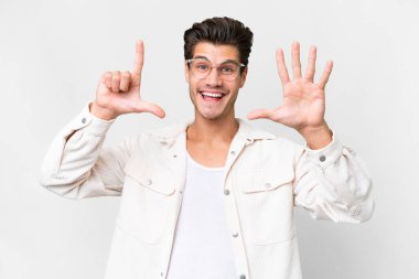 İzole edilmiş beyaz arka planda genç beyaz adam parmaklarıyla yediyi sayıyor.