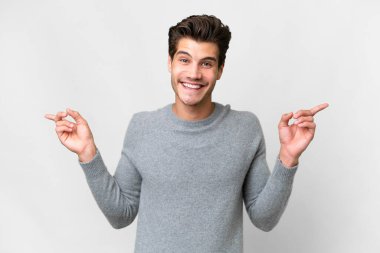 Soyutlanmış beyaz arka planda genç, yakışıklı, beyaz bir adam parmak uçlarında ve mutlu.