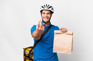 Young caucasian man taking a bag of takeaway food over isolated background doing coming gesture
