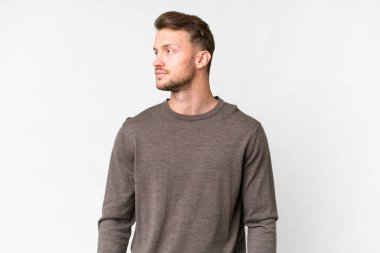 Beyaz arka planda beyaz tenli yakışıklı bir adam yan tarafa bakıyor.