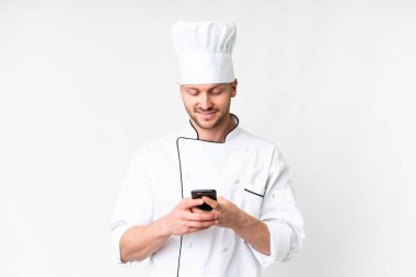 Kafkasyalı genç aşçı, izole edilmiş beyaz arka planda cep telefonuyla mesaj gönderiyor.