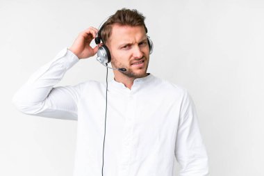 Tele pazarlamacı, beyaz arka plan üzerinde kulaklıkla çalışan beyaz bir adam. Şüpheleri var ve kafası karışmış bir yüz ifadesi var.