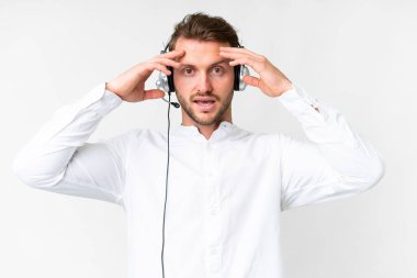 Tele pazarlamacı beyaz bir adam, izole edilmiş beyaz bir arka planda, sürpriz bir ifadeyle çalışıyor.