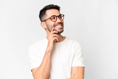 İzole edilmiş beyaz arka planı olan yakışıklı beyaz bir adam yukarı bakarken bir fikir düşünüyor.