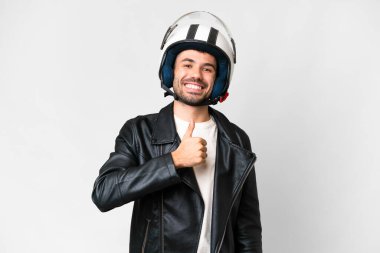 Motosiklet kasklı, beyaz arka planda genç, beyaz bir adam baş parmak hareketi yapıyor.