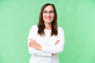 Middle age woman over isolated chroma key background keeping the arms crossed in frontal position