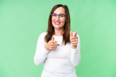 Orta yaşlı kadın izole edilmiş krom anahtar geçmişi şaşırmış ve ön tarafı işaret ediyor.