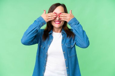 İzole edilmiş krom anahtar geçmişi olan orta yaşlı bir kadın gözlerini elleriyle kapatıyor.