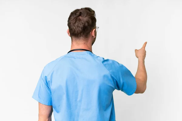 Jonge Verpleegkundige Man Geïsoleerde Witte Achtergrond Wijzen Terug Met Wijsvinger — Stockfoto