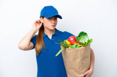 Young delivery woman taking a bag of takeaway food isolated on white background having doubts