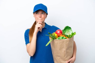 Genç teslimatçı kadın beyaz arka planda izole edilmiş bir paket yiyecek alıyor. Şüpheleri ve düşünceleri var.