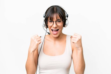 Telemarketer caucasian woman working with a headset over isolated background celebrating a victory in winner position