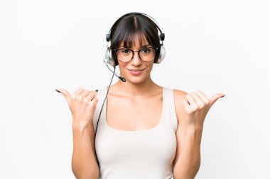Telemarketer caucasian woman working with a headset over isolated background with thumbs up gesture and smiling