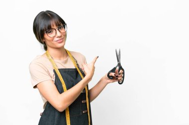 Young caucasian seamstress over isolated white background pointing back
