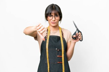 Young caucasian seamstress over isolated white background showing thumb down with negative expression