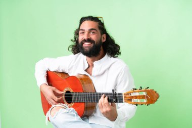 Young man with beard with guitar over isolated chroma key background