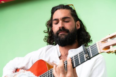 Young man with beard with guitar over isolated chroma key background